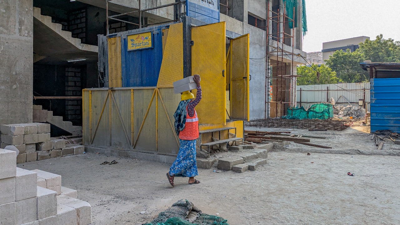A women at a construction site carrying bricks